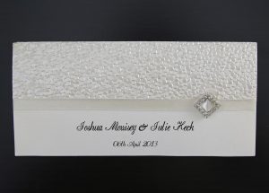 WEDINV11 front of cream wedding invitation with pebbles embossed paper ribbon and diamond diamante